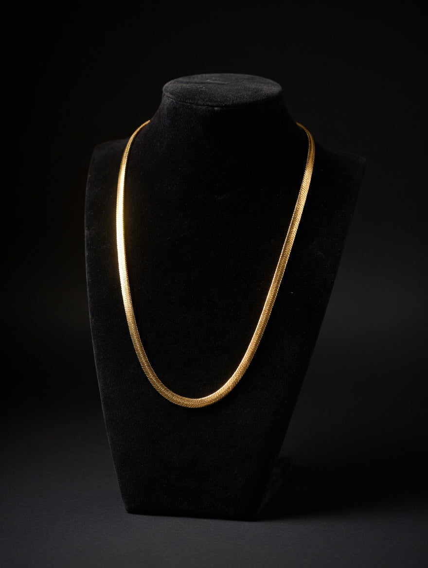 gold snake chain on mannequin bust in front of a black background