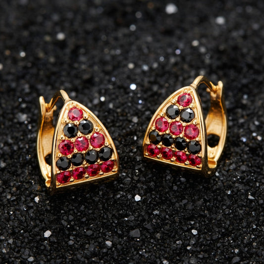 Gold earrings with red and black gemstones on a black glitter background