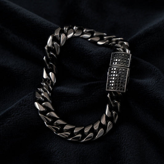 black cuban chain bracelet with a clasp on a dark fabric background