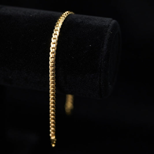 Gold tight linked cuban chain bracelet on a black velvet cushion
