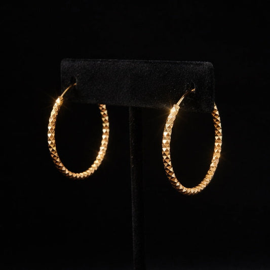 Gold hoop earrings on a black stand against a dark background