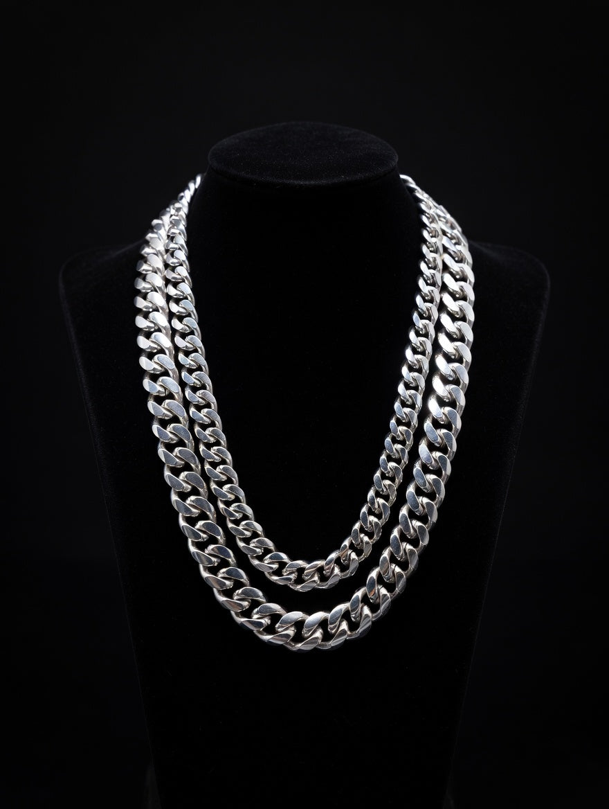 Two Miami Cuban Silver chain necklaces on a black mannequin against a black background
