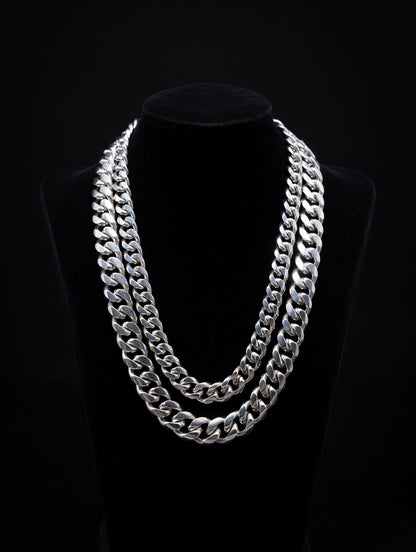 Two Miami Cuban Silver chain necklaces on a black mannequin against a black background