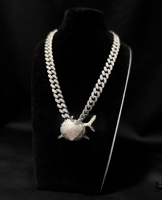 Silver chain necklace with a shark pendant on a black stand against a dark background