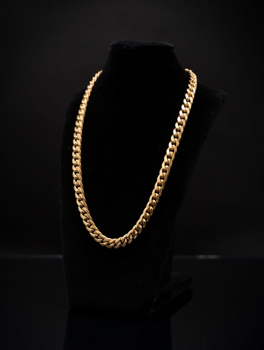 Gold chain necklace on a black mannequin against a black background