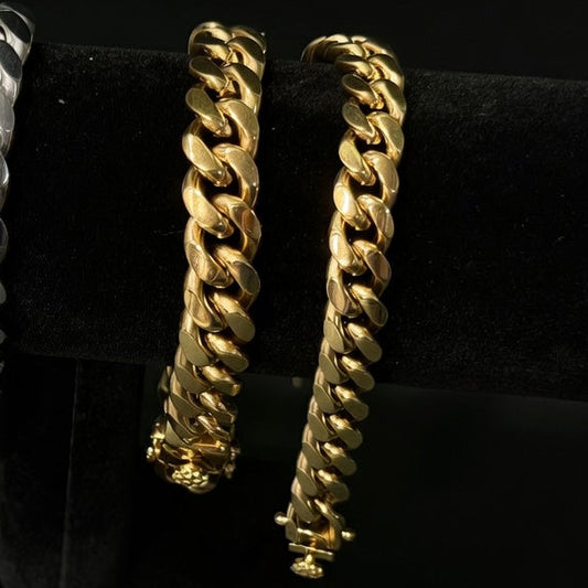 Pair of gold Miami cuban chains on a black stand.